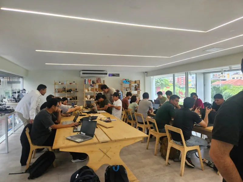 Builders trabajando en equipos alrededor de mesas con sus laptops